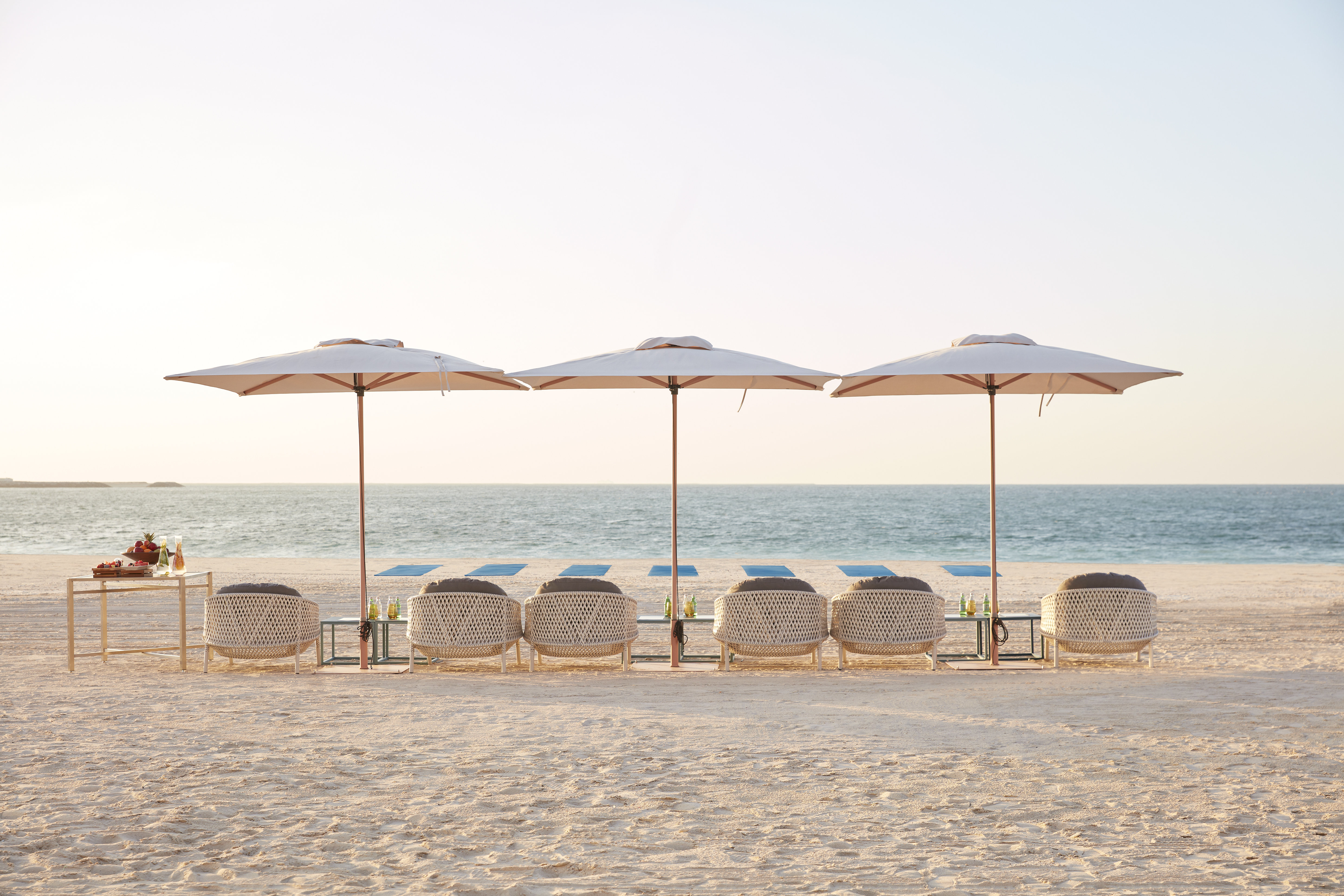 Beach loungers and umbrellas set on the private beach at Mandarin Oriental Jumeira, Dubai with the Arabian Gulf beyond - a property whose summer rates fall to the lowest of the year while the beach service stays fully staffed