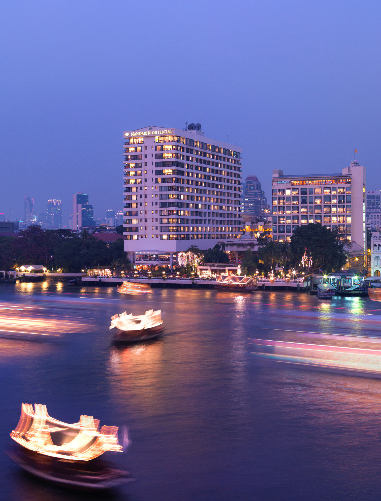 Mandarin Oriental Bangkok exterior view from the Chao Phraya River — the historic Author's Wing visible alongside the contemporary River Wing tower