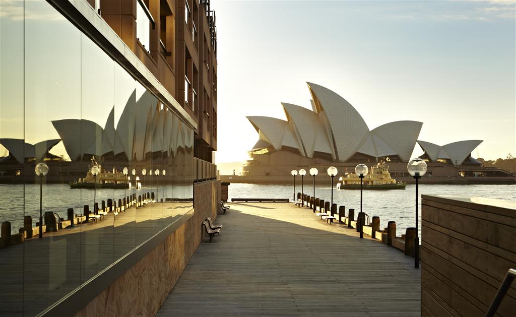 The Campbell's Cove boardwalk at Park Hyatt Sydney at first light with the substantial floor-to-ceiling glass reflecting the dedicated Sydney Opera House orientation across the harbour