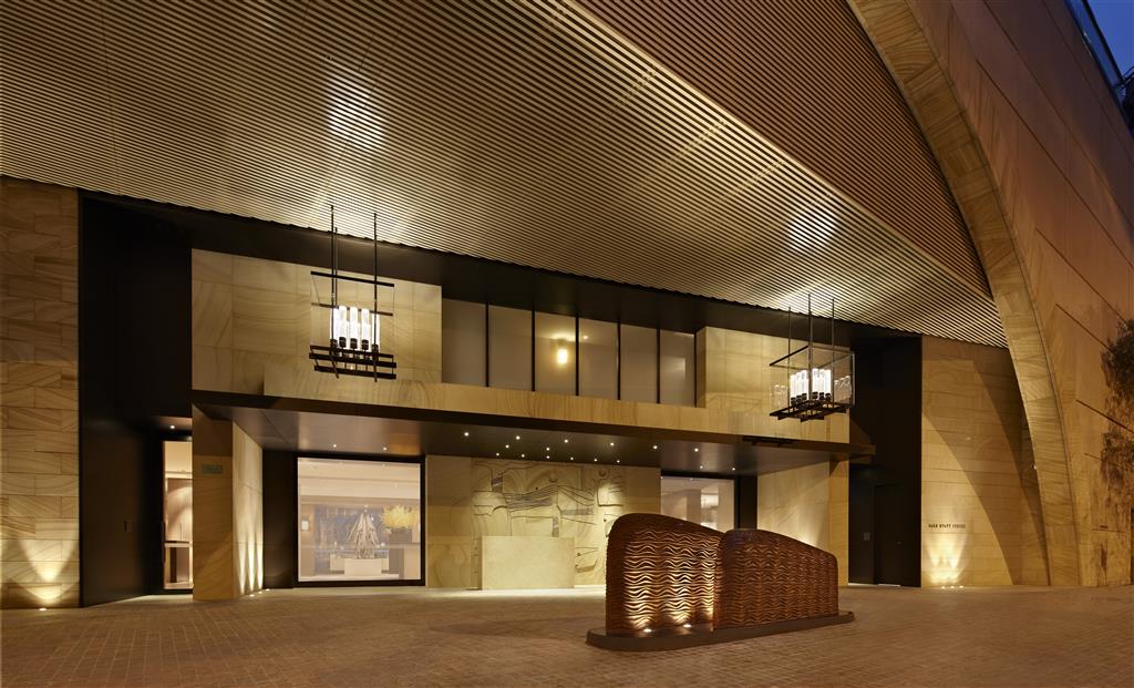 The sandstone entrance of Park Hyatt Sydney at dusk with sculptural artwork and layered lighting - the arrival infrastructure of doormen, valet, and porters that a true 5-star includes as standard