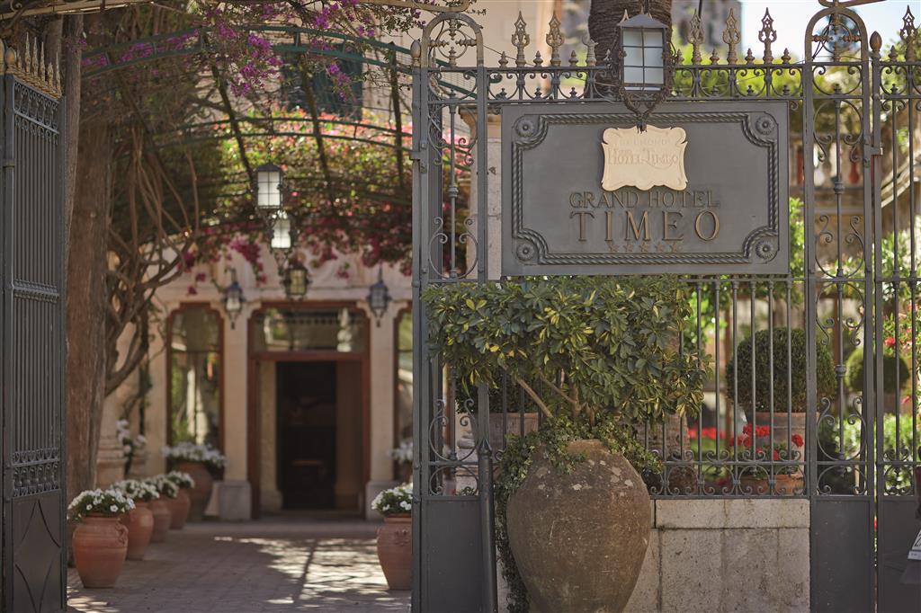 The iron gate and brass plaque of Belmond Grand Hotel Timeo in Taormina with bougainvillea and terracotta urns beyond - in Italy the stars on the plaque are an official regional classification, not a marketing claim