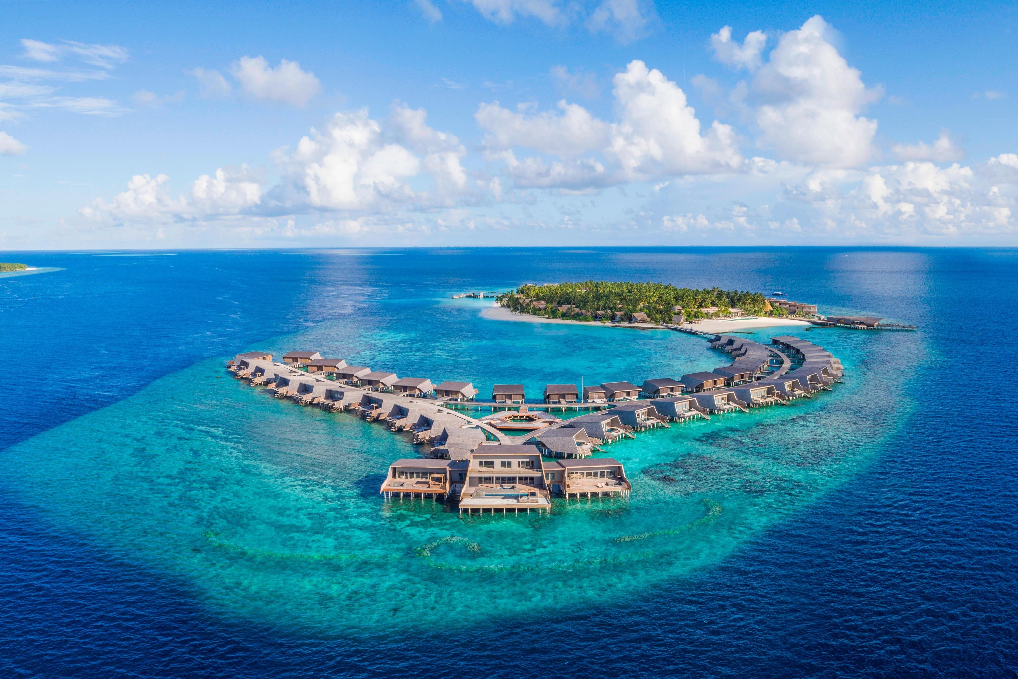 The celebrated Vommuli House overwater entertainment configuration at St. Regis Maldives Vommuli with the dramatic Manta-Ray-inspired architectural identity that defines the property's iconic central pavilion programming
