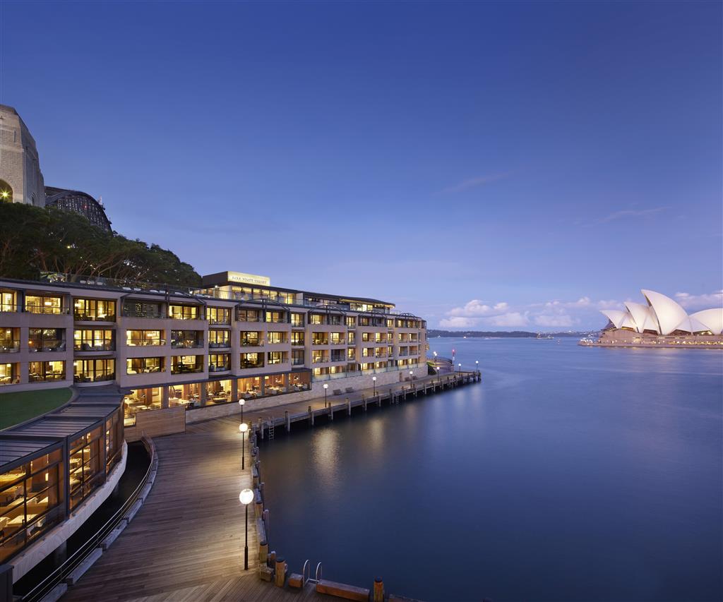 Park Hyatt Sydney at dusk on Campbell's Cove with the substantial low-rise waterline configuration beneath the Harbour Bridge and the dedicated Sydney Opera House orientation across Sydney Cove