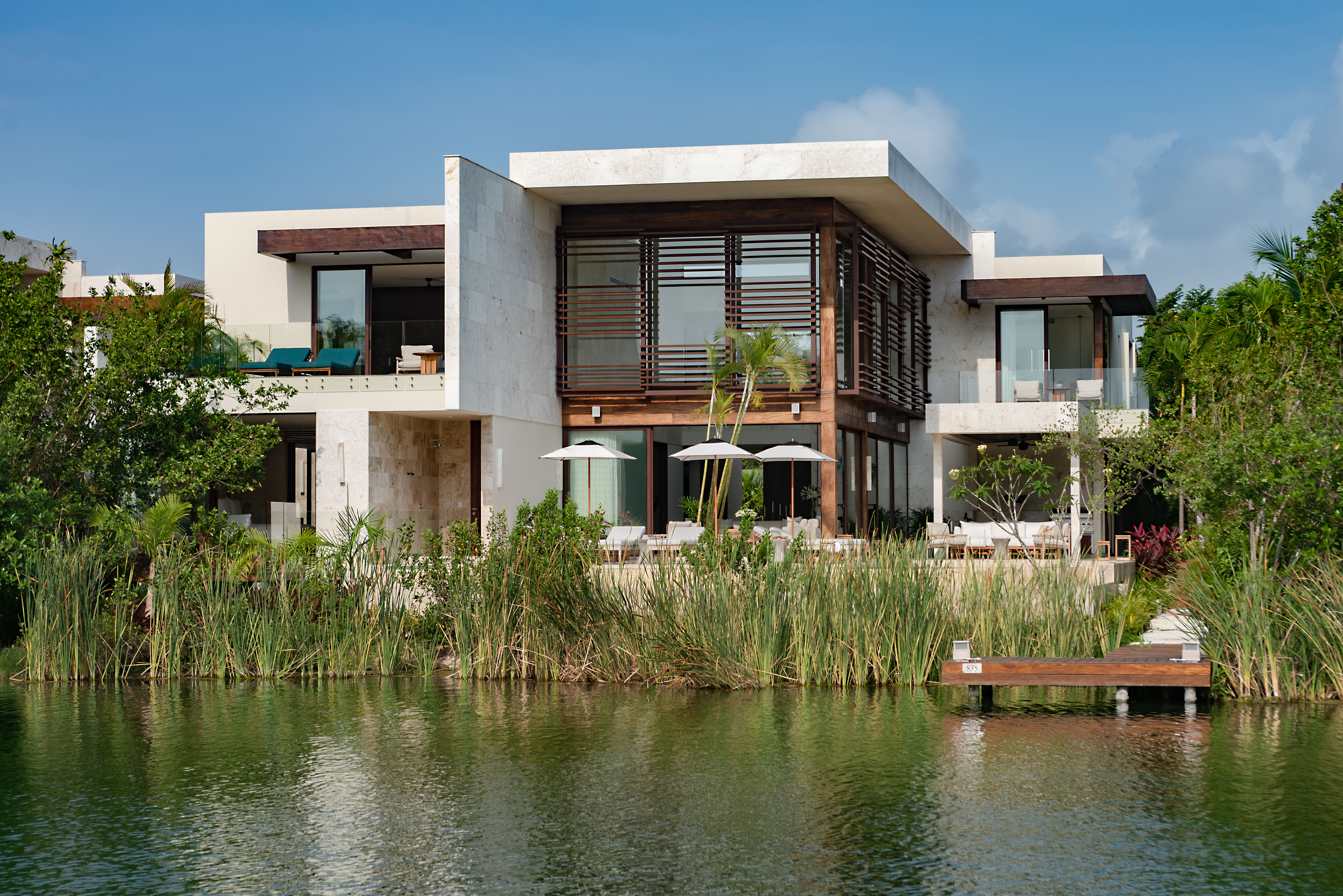 Rosewood Mayakoba traditional Mexican panga boat navigating the freshwater canal network that connects the resort buildings — the unique transportation system that defines the property's arrival sequence