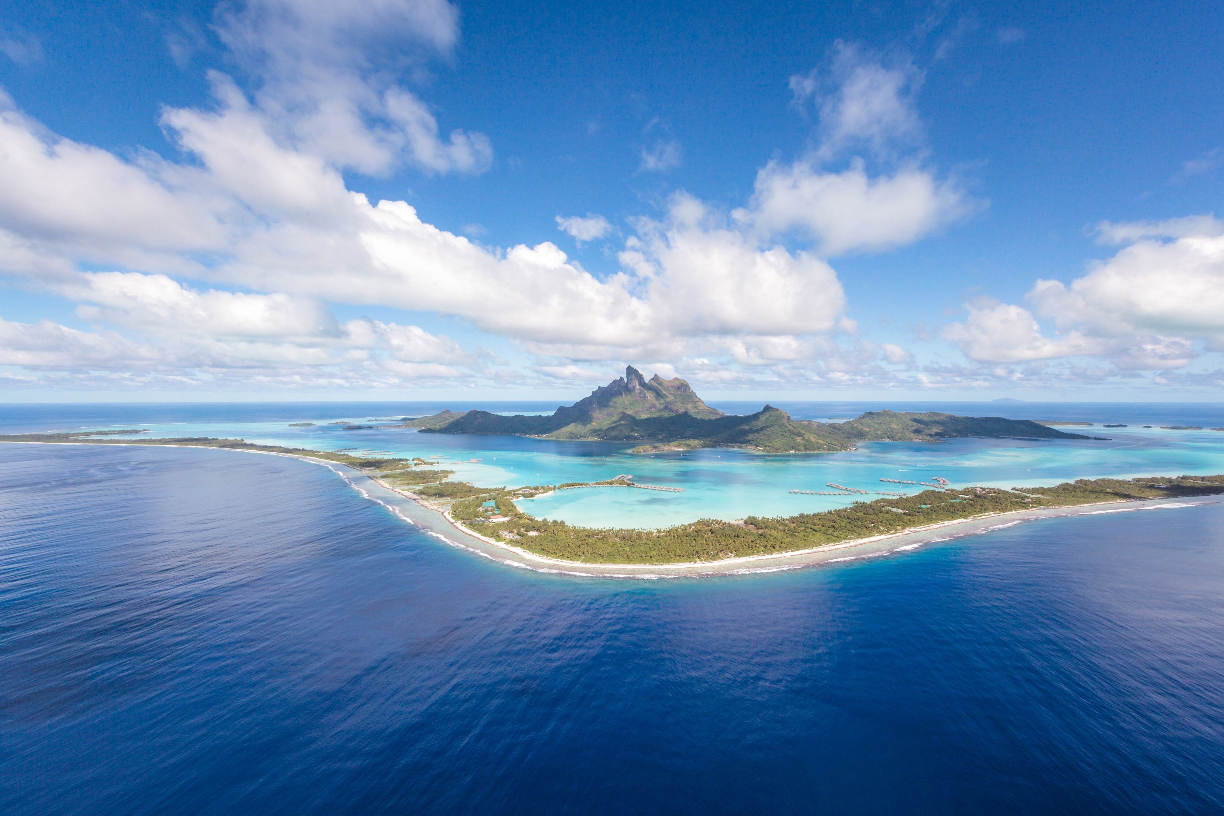 Overwater villa at St. Regis Bora Bora with private deck extending over the turquoise lagoon and Mount Otemanu visible in the distance